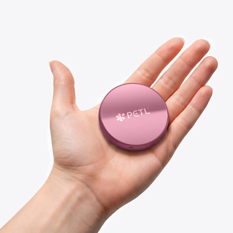 A hand holding a purple PETL MagSafe battery pack with the PETL logo visible on its circular surface.